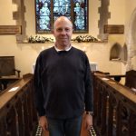 Paul Harrison, churchwarden standing in the front of the east window in St Mary Magdalene